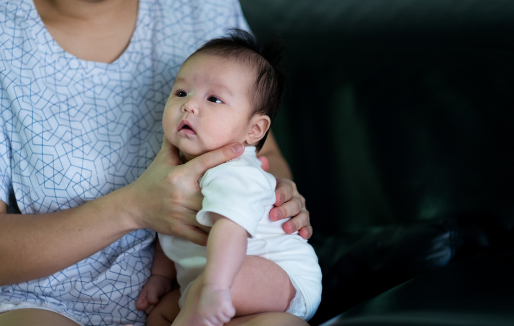 Un adulte qui tient un bébé à plat ventre sur ses cuisses.