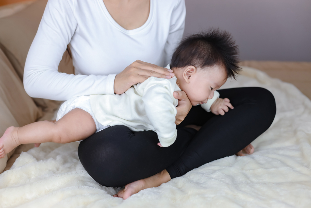Un adulte qui tient un bébé sur ses genoux, une main soutenant son menton et l’autre dans son dos.