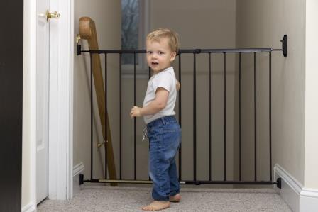 Un bébé debout à côté d’une barrière de sécurité empêchant l’accès aux escaliers