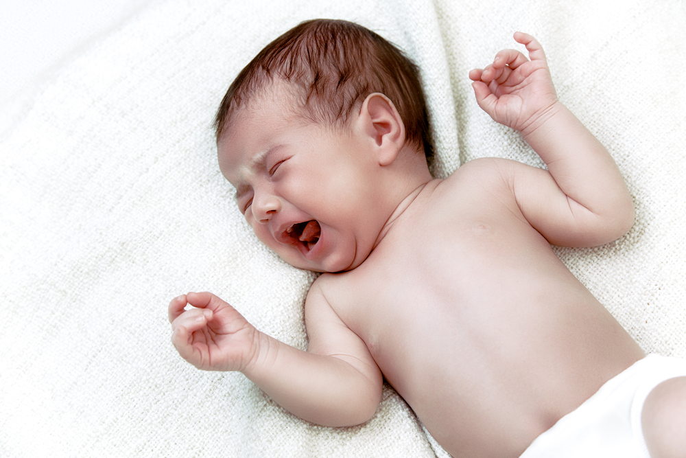  A baby crying with their head turned to the side.