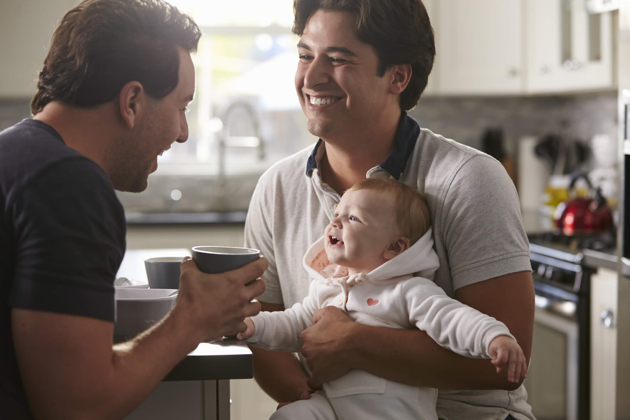 two fathers entertaining their baby