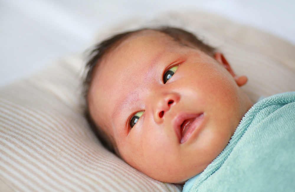 Bébé couché sur un oreiller rayé, enveloppé dans une couverture bleu clair