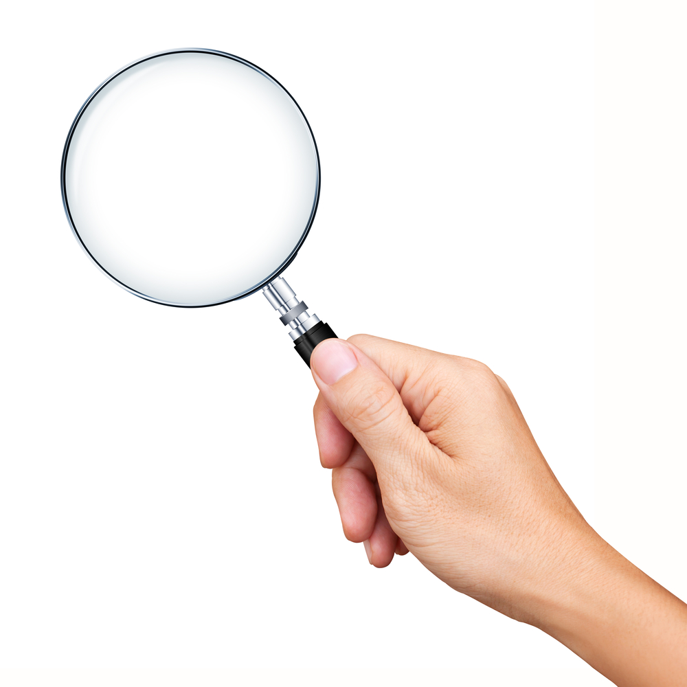 A hand holding a magnifying glass