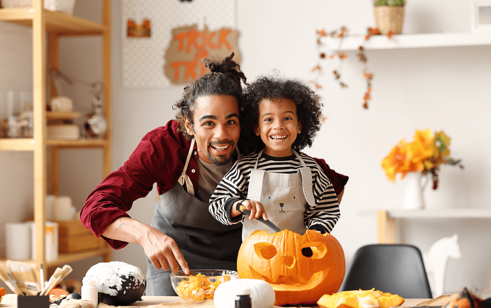 Parent and child carving a pumpkin together. 