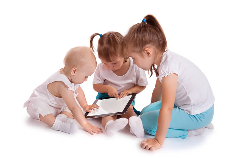 Trois jeunes enfants assis sur le plancher et interagissant avec une tablette