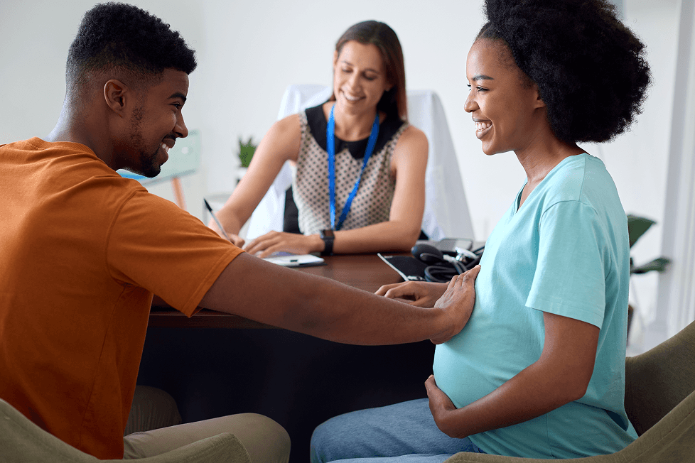 Couple de futurs parents lors d’un rendez-vous avec une femme médecin dans son cabinet.