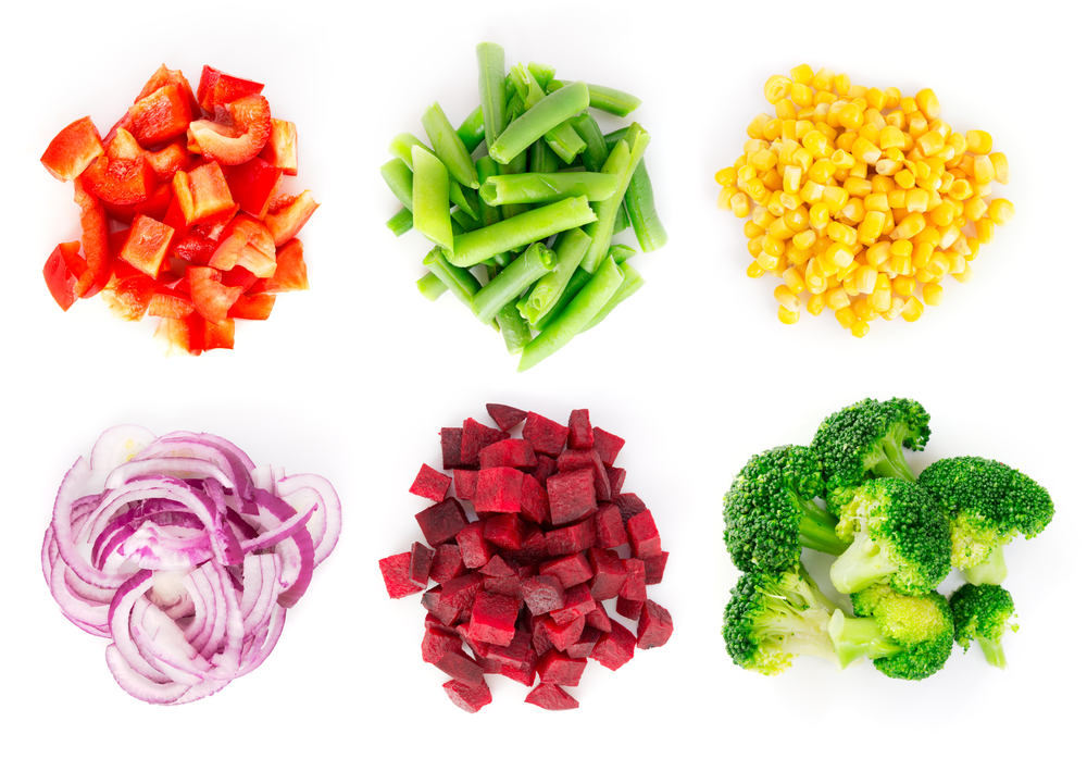Des piles de légumes colorés comme du maïs, du poivron rouge, du brocoli, de la betterave et un oignon rouge